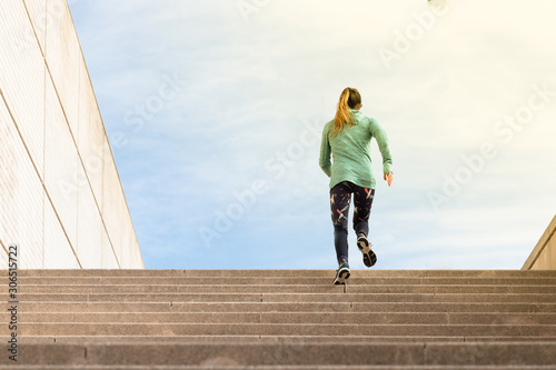 Fototapeta Naklejka Na Ścianę i Meble -  Back view of young female athlete running stairs up.