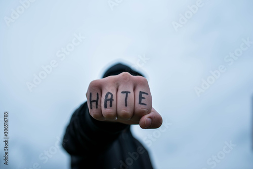 Frustrated , aggressive teenage boy showing hes fist with the word hate, shallow depth of field.