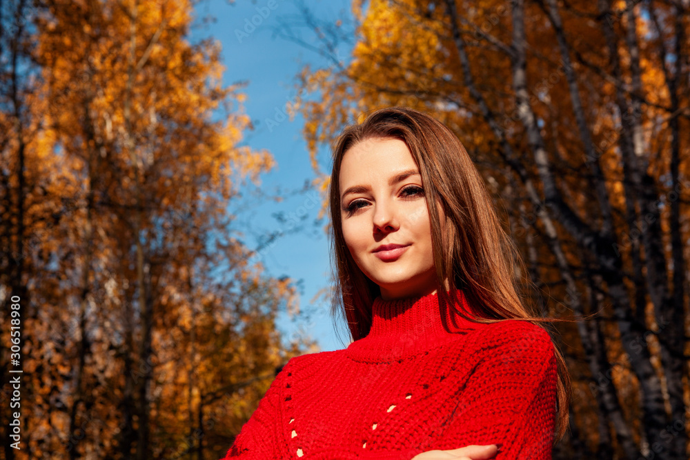 Young woman posing in red sweater in autumn park.