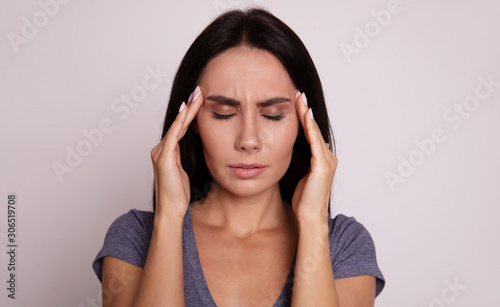 Wallpaper Mural Headache. Full-face portrait of a girl, who is facing the camera with her eyes closed and her fingers touching temples as a sign of stress or headache. Torontodigital.ca