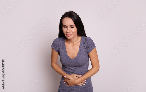 Belly ache. Close-up photo of a young brunette, who is holding her stomach with her hands, indicating that she is having a stomach ache.