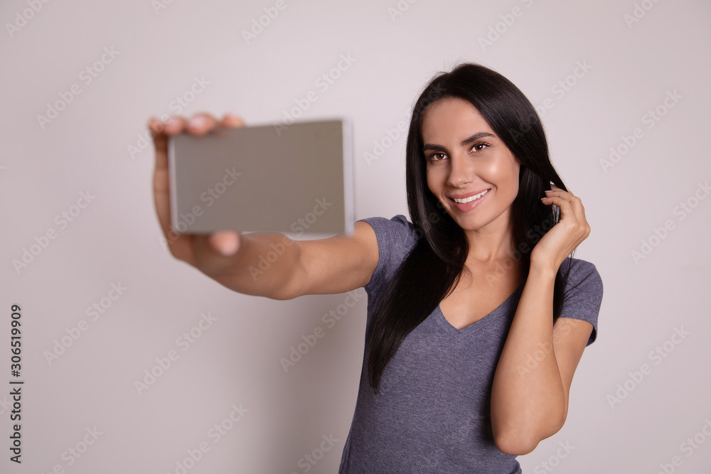 Princess charming. Close-up photo of an attractive woman with long jet-black hair, who holds a smartphone in her right hand, while taking a selfie and smiling broadly. Princess charming. Close-up photo of an attractive woman with long jet-black hair, who holds a smartphone in her right hand, while taking a selfie and smiling broadly.