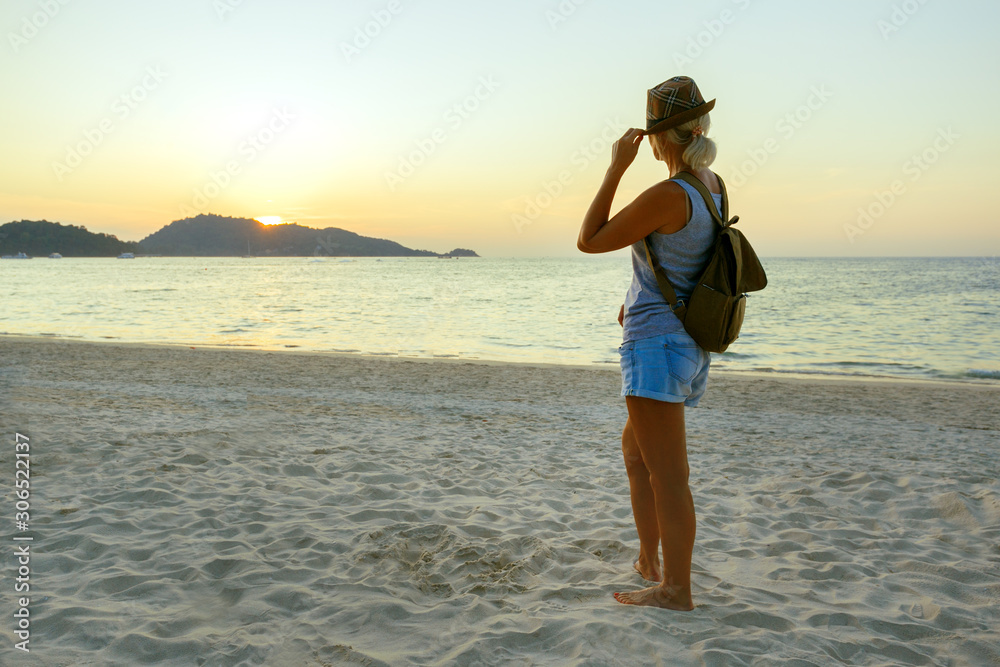 Happy Woman in Hat Enjoying Beautiful Sunset on the Beach. Travel in Asia concept. Tropical background.