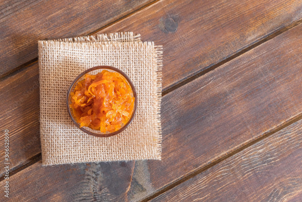 Glass bowl of homemade carrot jam with carrots and orange on concrete background Glass bowl of homemade carrot jam with carrots and orange on concrete background