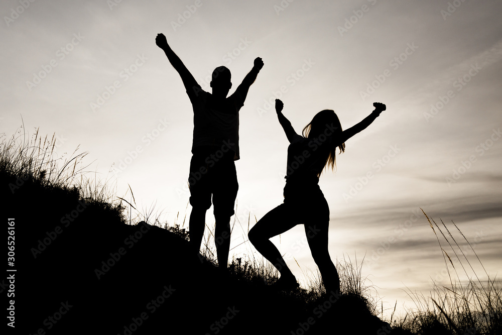 Siluetas de una pareja (chico y chica) con las manos en alto mirándo hacia delante y de perfil en una puesta de sol mientras hacían deporte (trekking) por el monte (montaña) en Andalucia. en color Siluetas de una pareja (chico y chica) con las manos en alto mirándo hacia delante y de perfil en una puesta de sol mientras hacían deporte (trekking) por el monte (montaña) en Andalucia. en color