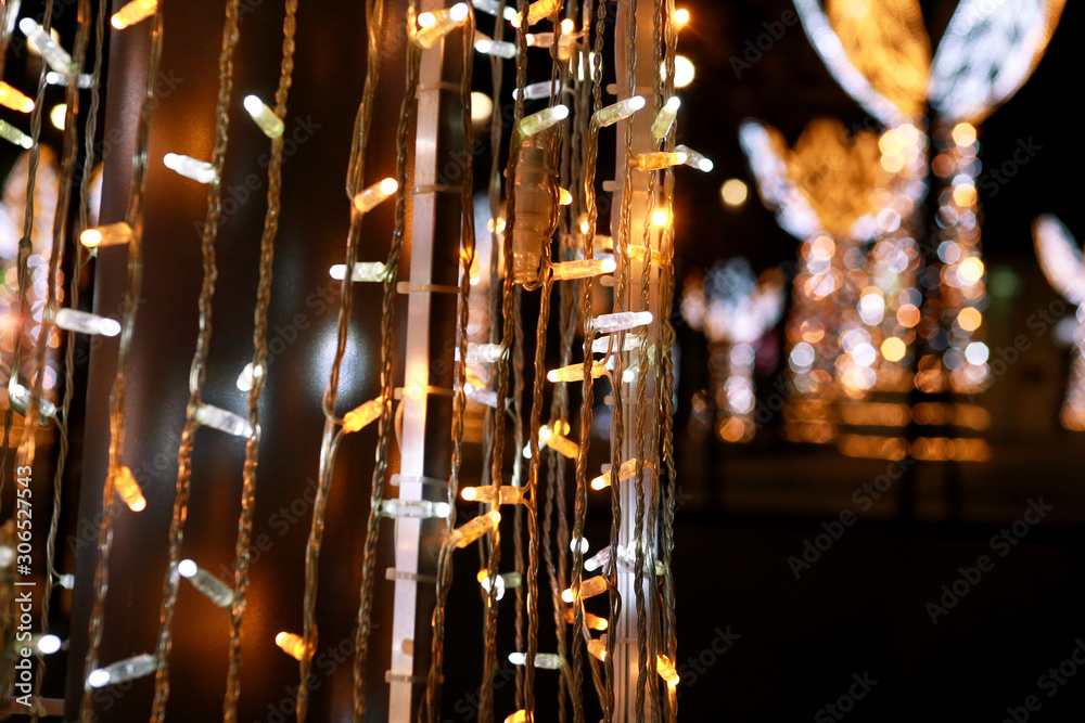 Obraz premium Part of Christmas decorative silver, white, yellow, golden flashing lights. Detail of New Year and Christmas decorations, string rice lights bulbs. Ornaments to christmas celebration, holiday scene.