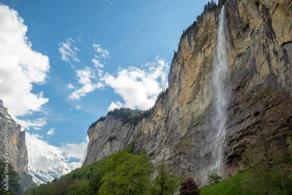 Obraz premium Staubbach waterfall in Lauterbrunnen on blue sky with clouds background with copy space , Switzerland