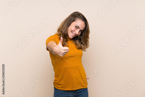 Young blonde girl over isolated background with thumbs up because something good has happened © luismolinero