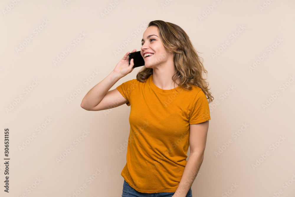 Young blonde girl over isolated background keeping a conversation with the mobile phone Young blonde girl over isolated background keeping a conversation with the mobile phone