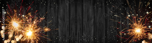 Silvester New Year 2024 New Year's Eve background banner panorama long- sparklers, firework and bokeh lights on rustic wooden texture, top view with space for text