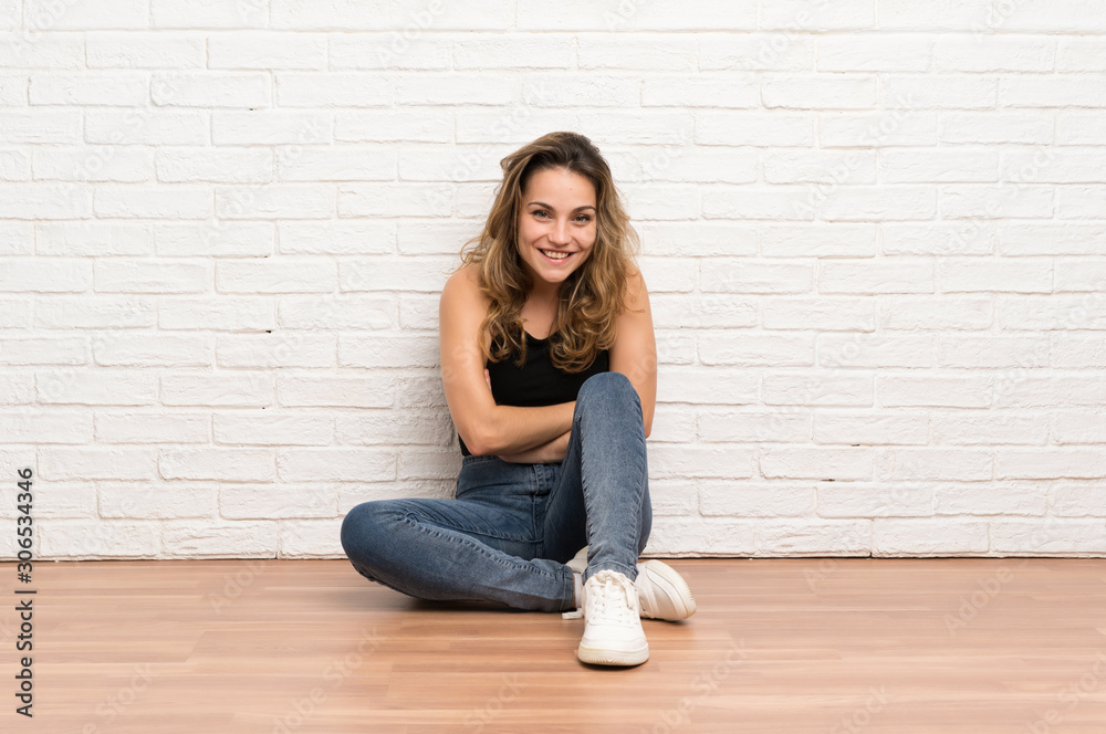 Young blonde woman sitting on the floor laughing Young blonde woman sitting on the floor laughing