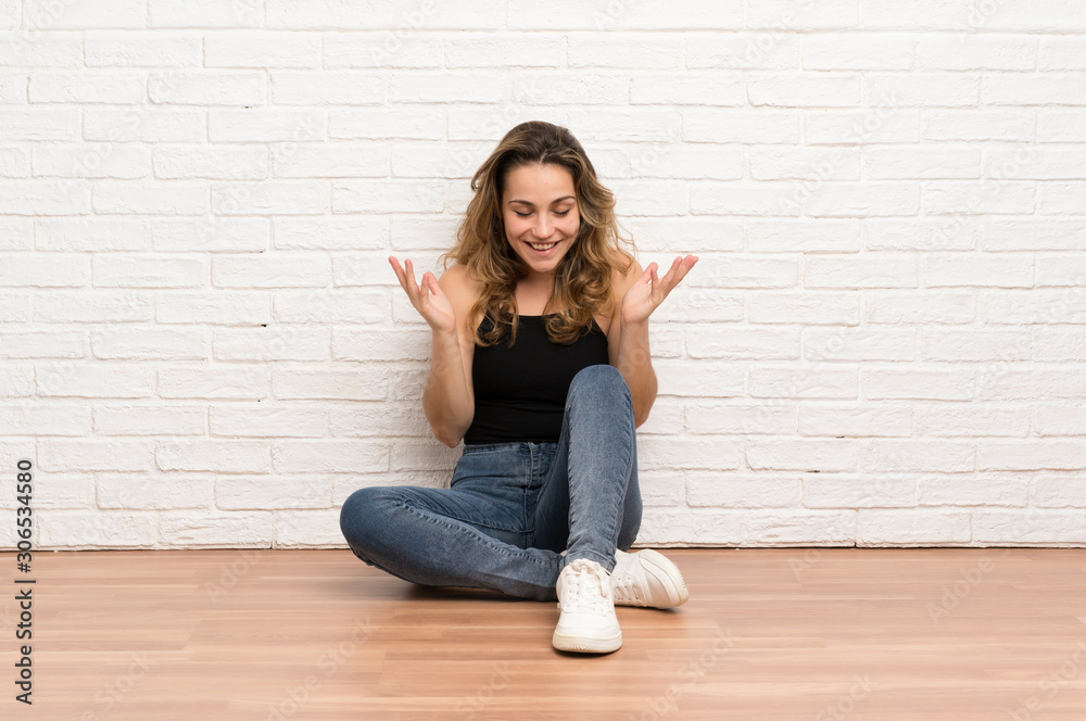 Young blonde woman sitting on the floor laughing Young blonde woman sitting on the floor laughing