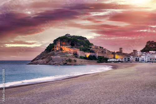 The Spanish city of Tossa de Mar located in Costa Brava is a coastal region of Catalonia. Beautiful sunset sky, an ancient cliff fort, sandy beach and the Mediterranean Sea.