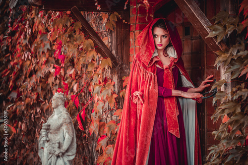 Beautiful girl in a burgundy coat and red dress open door in castle © popovatetiana