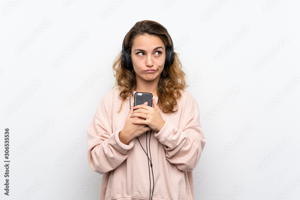 Young blonde woman using the mobile with headphones and thinking Young blonde woman using the mobile with headphones and thinking