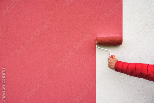  hand holds paint roller and painting a wall photo