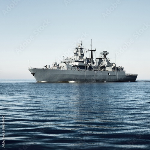 Foto Grey modern warship sailing in still water