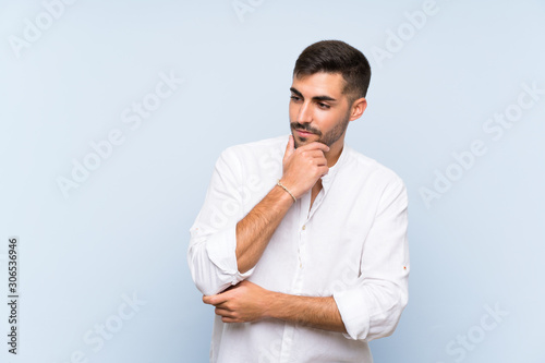 Handsome man with beard over isolated blue background looking to the side © luismolinero