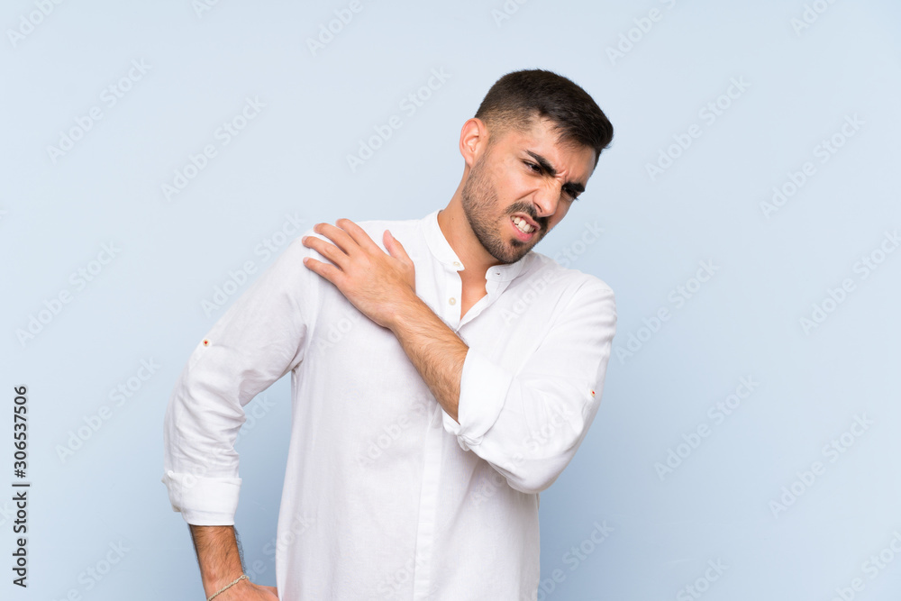 Handsome man with beard over isolated blue background suffering from pain in shoulder for having made an effort Handsome man with beard over isolated blue background suffering from pain in shoulder for having made an effort