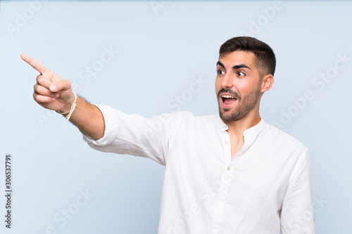 Handsome man with beard over isolated blue background pointing away