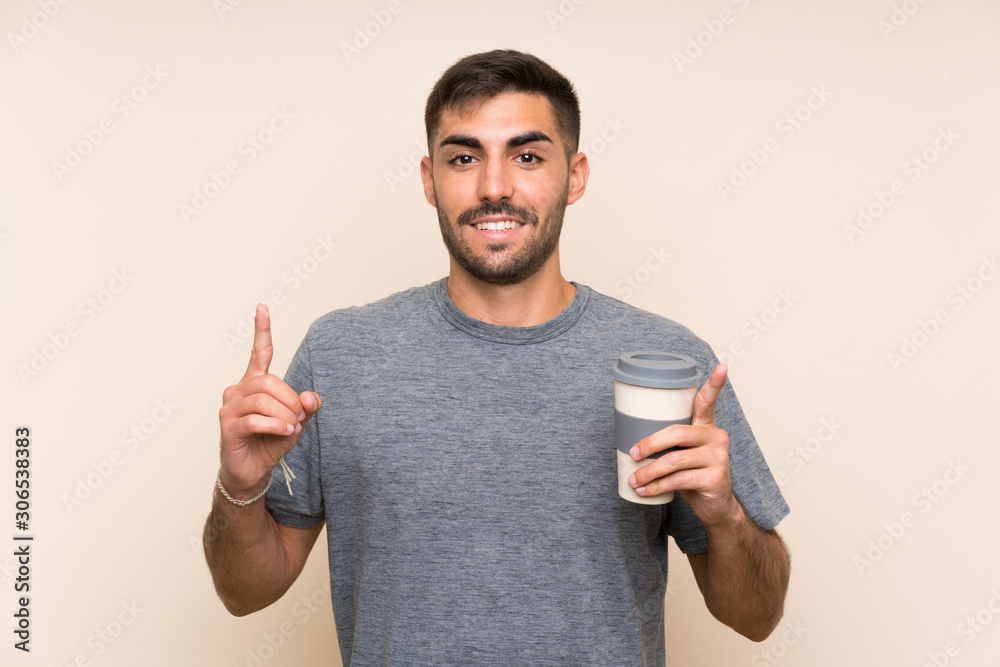 Handsome man with beard holding a take away coffee over isolated background pointing up a great idea Handsome man with beard holding a take away coffee over isolated background pointing up a great idea