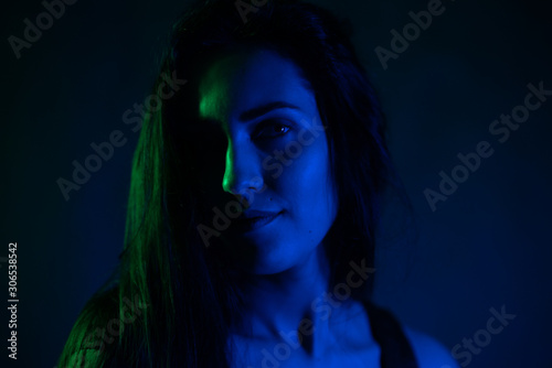 Studio portrait of a girl in the light of blue and green neon lights. on a black background.