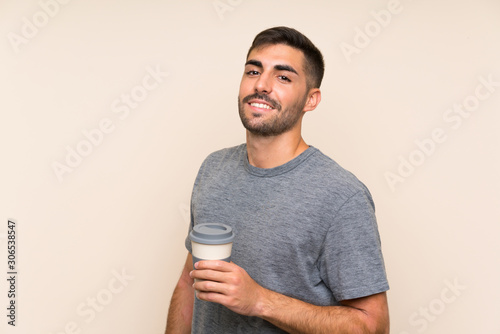Handsome man with beard holding a take away coffee over isolated background