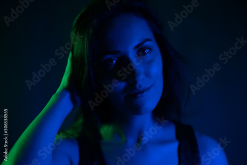 Studio portrait of a girl beautiful in the light of blue and green neon lights. on a black background.
