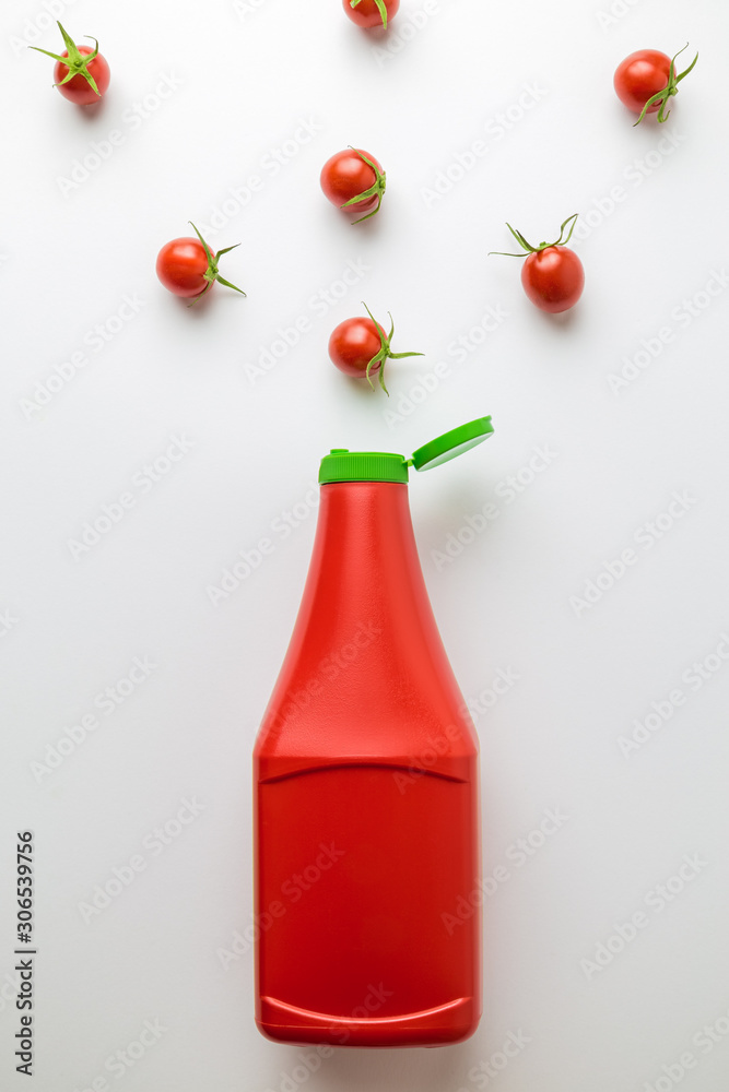Obraz premium Flat lay of plastic bottle of ketchup with cherry tomatoes pattern on white background minimal food creative concept. Space for copy.