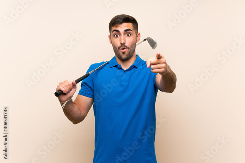 Young handsome golfer man over isolated background surprised and pointing front