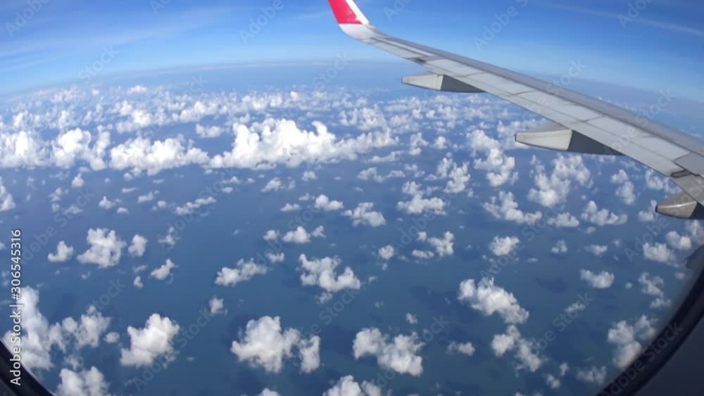 Looking through window aircraft during flight with a nice blue sky with clouds