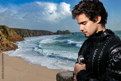 Portrait of knight holding sword, standing on balcony and praying with aquamarine ocean and blue sky in background