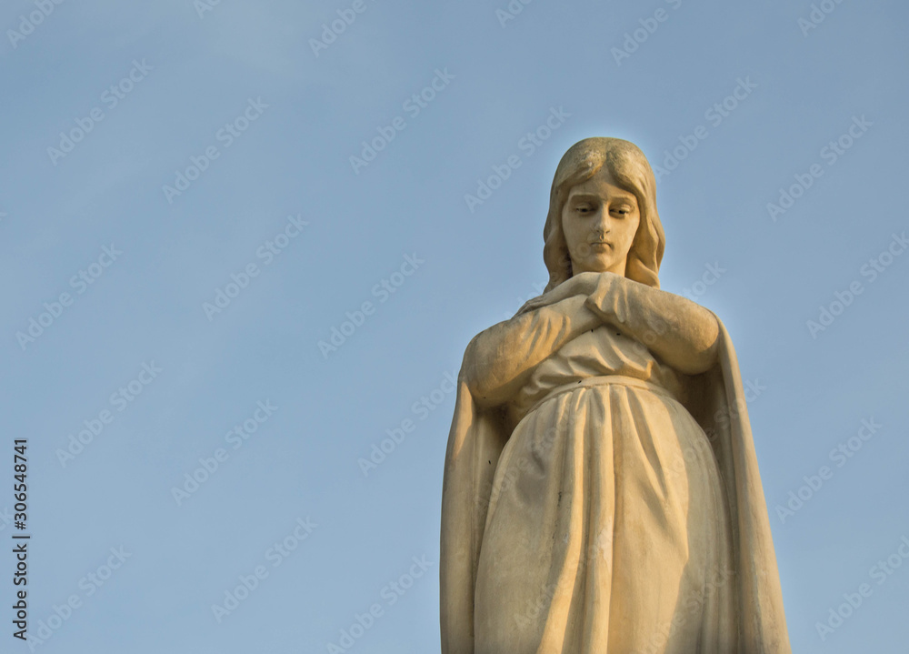 Monument and candles in the cemetery. All Saints Day in Poland. Stone sculpture. Stone angel.