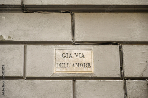 Close-up of the street sign in Via Sant'Antonino in Florence, which informs that once this same street was called the Street of Love (Via dell'Amore), on a gray wall background, Tuscany, Italy