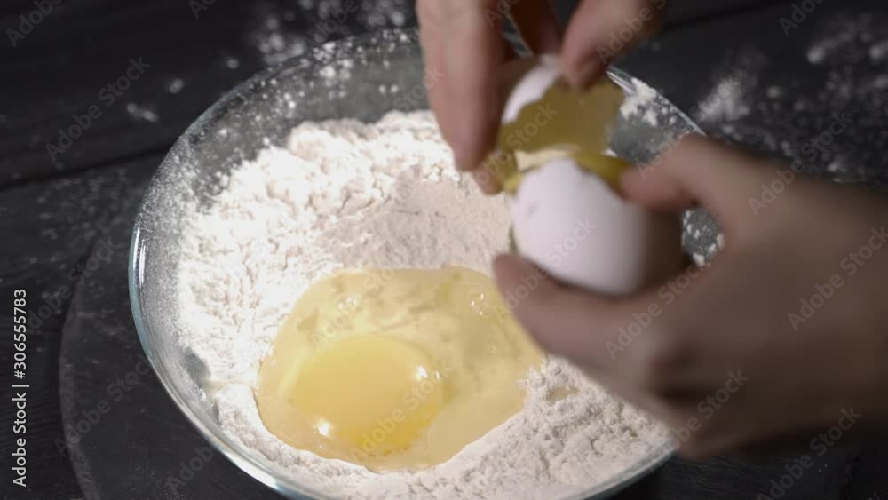 Break eggs into flour, close up and slow motion Break eggs into flour, close up and slow motion