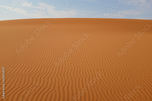 Desert sand ripples under a blue sky