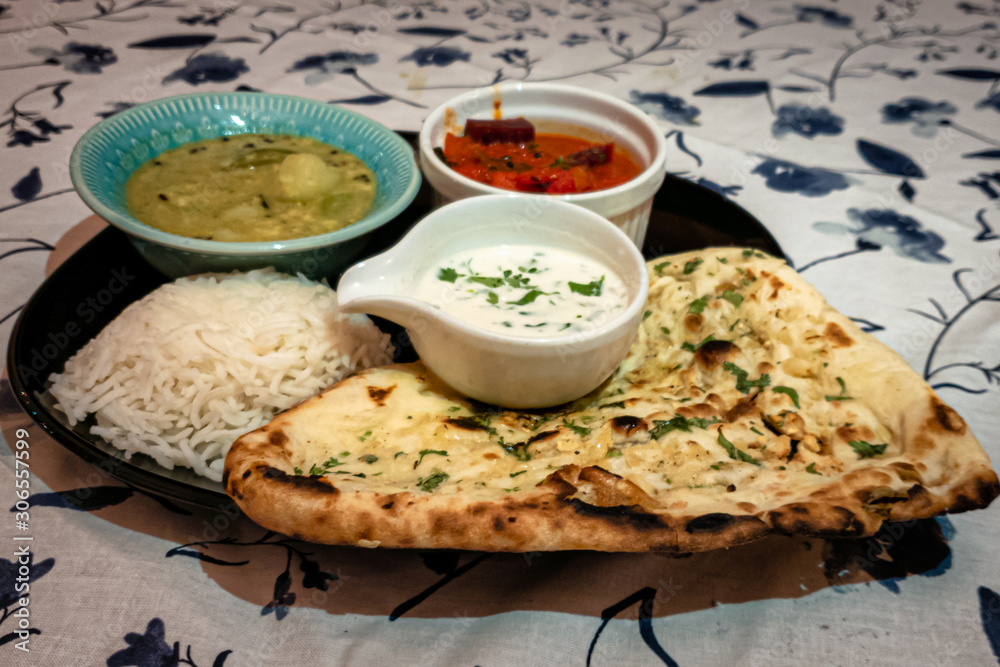 North indian home made thali with rice and nan bread served with curry and curd North indian home made thali with rice and nan bread served with curry and curd