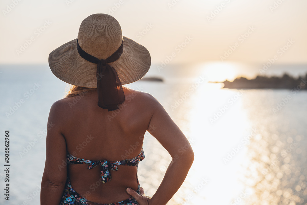 Young woman enjoying in sunset on the cliff at seaside