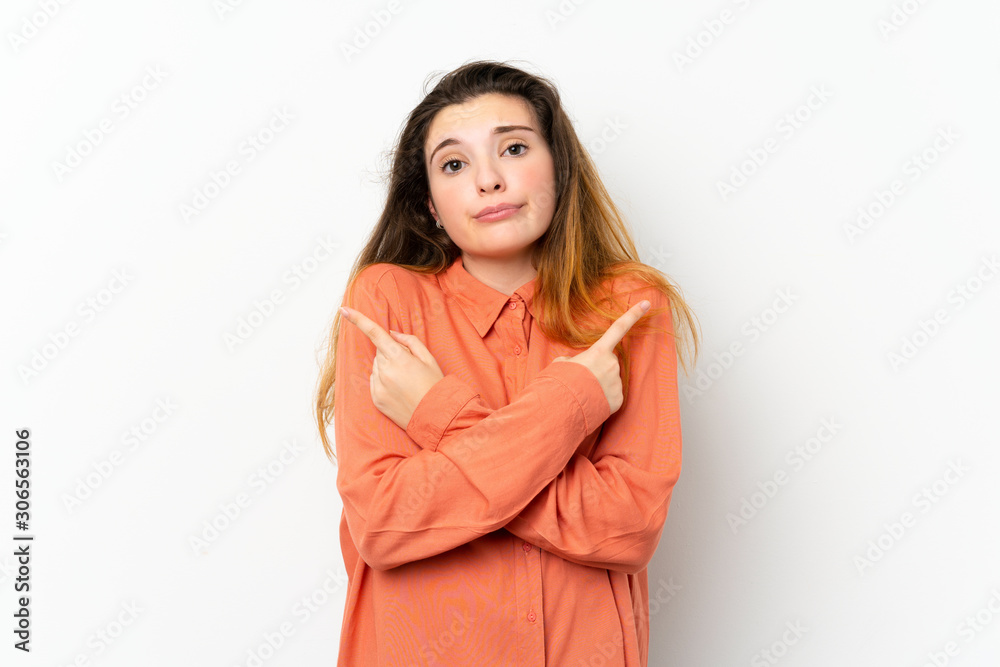 Young brunette girl over isolated white background pointing to the laterals having doubts Young brunette girl over isolated white background pointing to the laterals having doubts