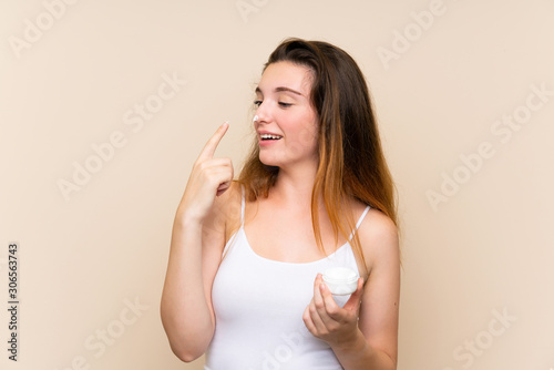 Young brunette girl with moisturizer over isolated background © luismolinero