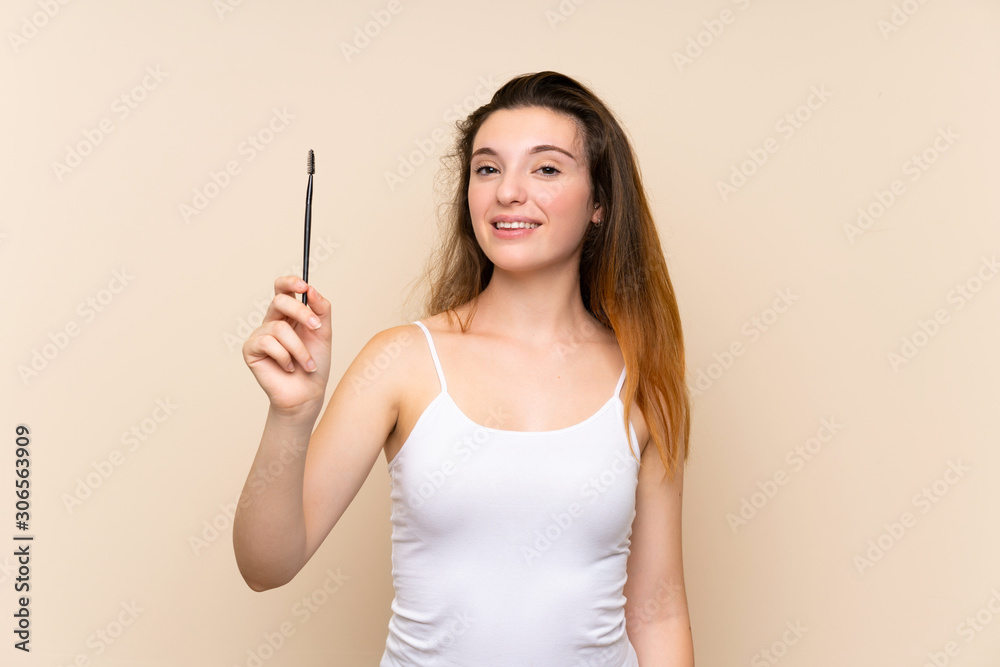 Young brunette girl applying mascara with cosmetic rush over isolated background Young brunette girl applying mascara with cosmetic rush over isolated background