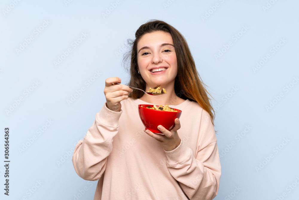 Young brunette girl over isolated blue background holding a bowl of cereals Young brunette girl over isolated blue background holding a bowl of cereals