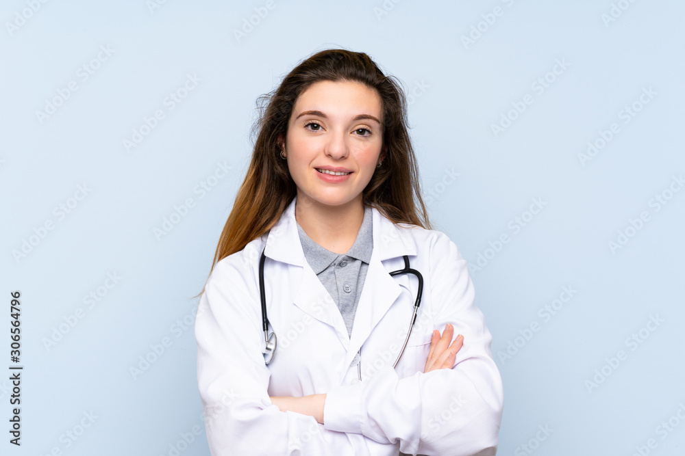 Young brunette girl over isolated blue background with doctor gown Young brunette girl over isolated blue background with doctor gown