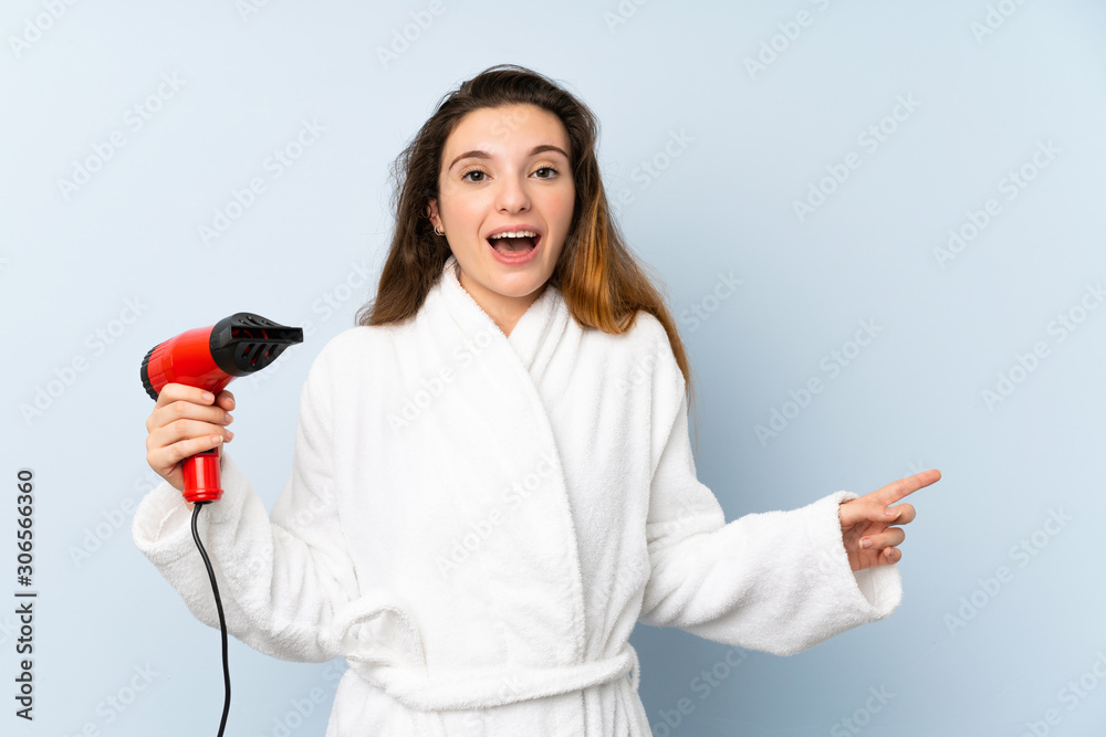 Young woman in a bathrobe with hair hairdryer surprised and pointing finger to the side Young woman in a bathrobe with hair hairdryer surprised and pointing finger to the side