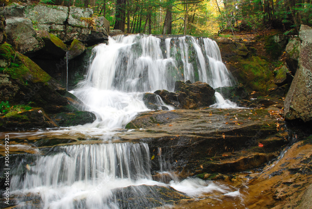 Cascading waterfall with smooth flowing water in the forest during autumn season Cascading waterfall with smooth flowing water in the forest during autumn season