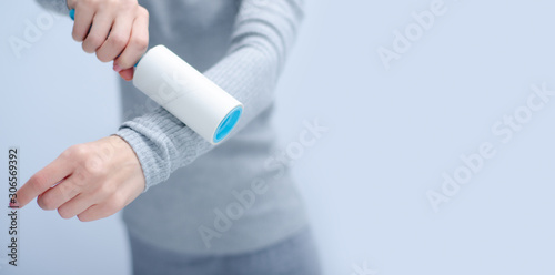 Woman holding roll for cleaning clothes on gray light background  space for text