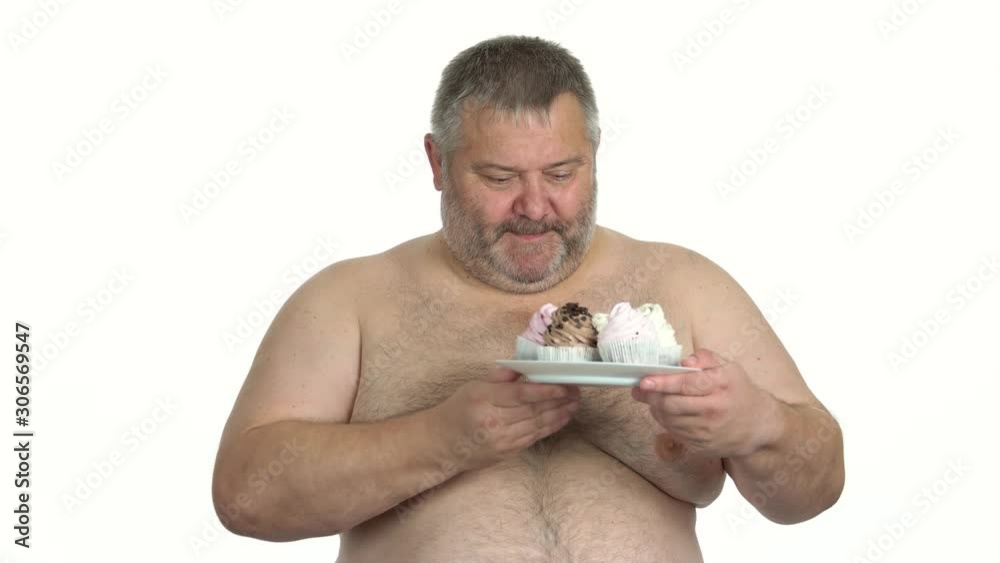 Fat shirtless man holding plate with cakes. Hungry obese man staring at sweet food. Isolated on white background. Fat shirtless man holding plate with cakes. Hungry obese man staring at sweet food. Isolated on white background.