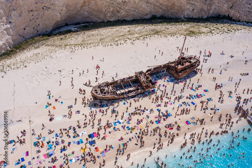 Fototapeta Naklejka Na Ścianę i Meble -  Tourists enjoy summer time by abandoned rusty ship on shipwreck navagio beach