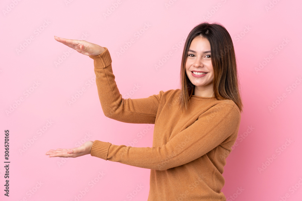 Young woman over isolated pink background holding copyspace to insert an ad Young woman over isolated pink background holding copyspace to insert an ad