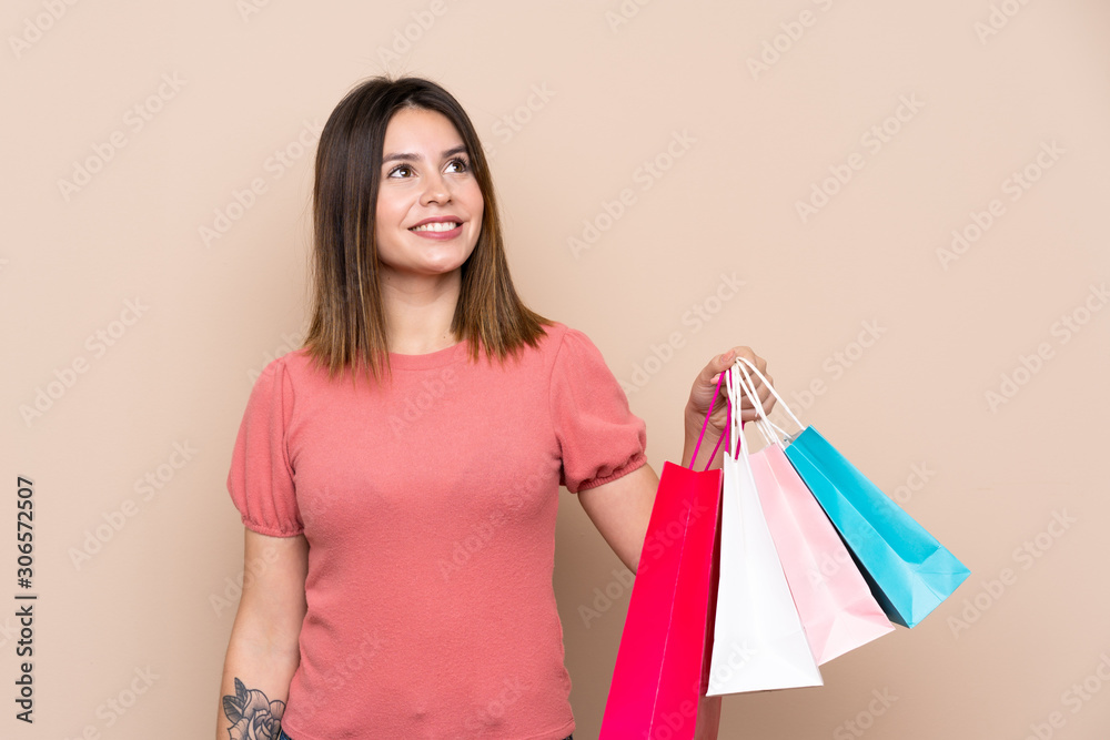 Young woman with shopping bag over isolated background looking up while smiling Young woman with shopping bag over isolated background looking up while smiling
